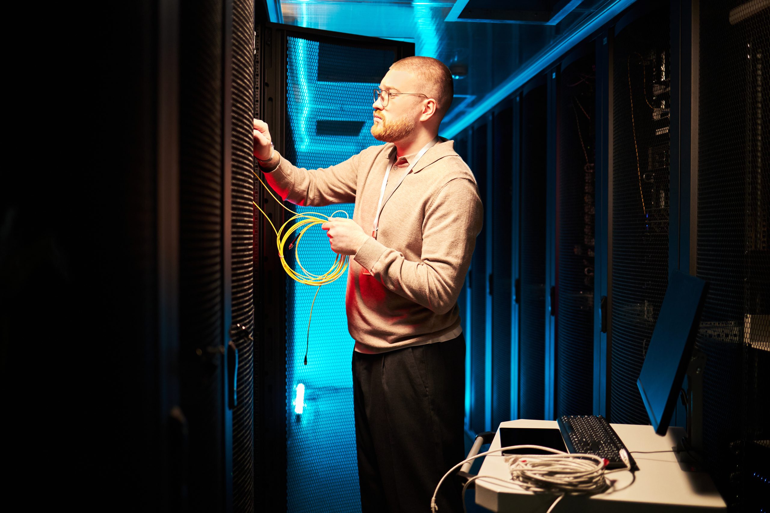Technician Connecting Network Cables in Server Room